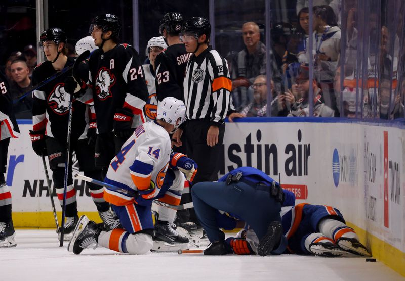 Nov 1, 2024; Buffalo, New York, USA;  Trainers attend to New York Islanders defenseman Mike Reilly (2) after getting hurt during the second period against the Buffalo Sabres at KeyBank Center. Mandatory Credit: Timothy T. Ludwig-Imagn Images