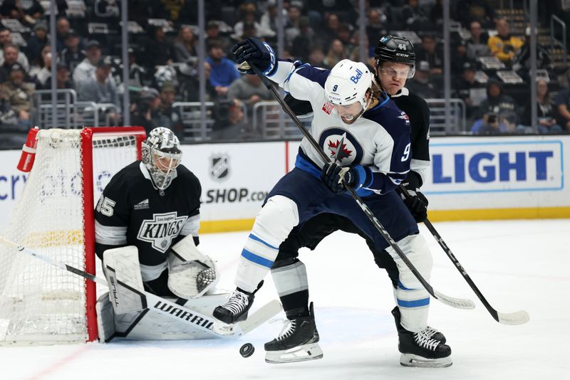 Apr 1, 2025; Los Angeles, California, USA;  Winnipeg Jets left wing Alex Iafallo (9) fights for the puck against Los Angeles Kings defenseman Mikey Anderson (44) during the first period at Crypto.com Arena. Mandatory Credit: Kiyoshi Mio-Imagn Images