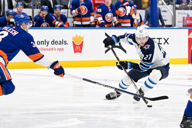 Mar 23, 2024; Elmont, New York, USA;  Winnipeg Jets left wing Nikolaj Ehlers (27) skates with the puck defended by New York Islanders defenseman Adam Pelech (3) during the third period at UBS Arena. Mandatory Credit: Dennis Schneidler-USA TODAY Sports