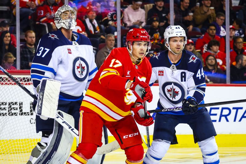 Oct 4, 2024; Calgary, Alberta, CAN; Calgary Flames center Yegor Sharangovich (17) and Winnipeg Jets defenseman Josh Morrissey (44) fights for position in front of Winnipeg Jets goaltender Connor Hellebuyck (37) during the second period at Scotiabank Saddledome. Mandatory Credit: Sergei Belski-Imagn Images