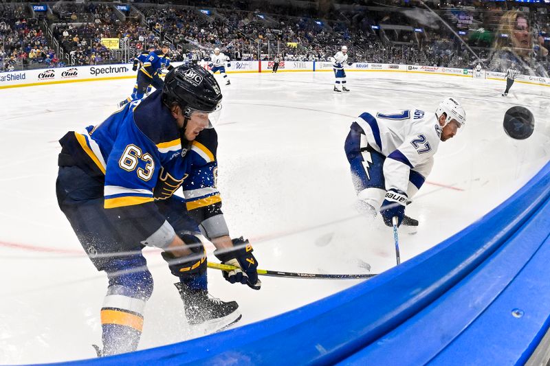 Nov 5, 2024; St. Louis, Missouri, USA;  St. Louis Blues left wing Jake Neighbours (63) and Tampa Bay Lightning defenseman Ryan McDonagh (27) b battle for the puck during the third period at Enterprise Center. Mandatory Credit: Jeff Curry-Imagn Images