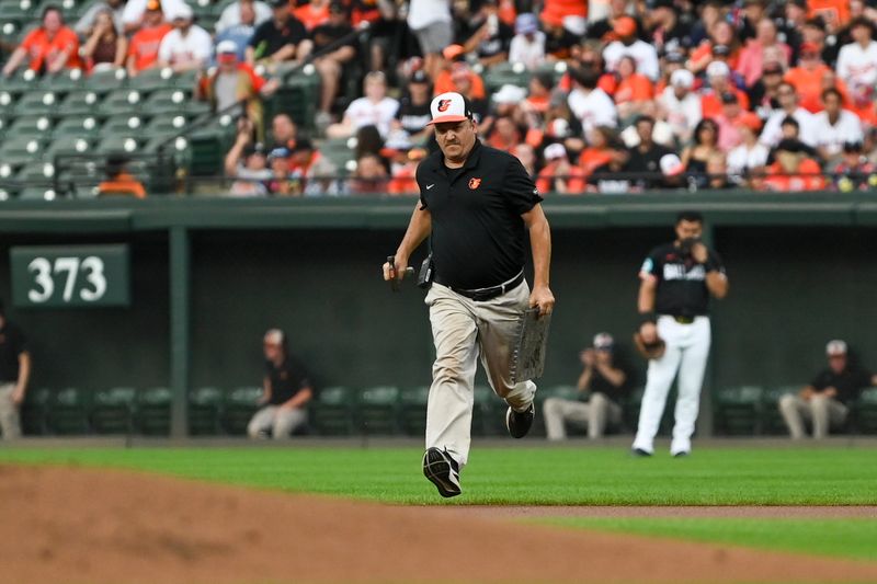 Aug 16, 2024; Baltimore, Maryland, USA;  A member of the Baltimore Orioles field crew runs to the pitcher's mound during a delay to the start of the game against the Boston Red Sox at Oriole Park at Camden Yards. Mandatory Credit: Tommy Gilligan-USA TODAY Sports