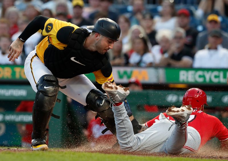 Aug 23, 2024; Pittsburgh, Pennsylvania, USA;  Cincinnati Reds left fielder Spencer Steer (right) slides home to score a run on a suicide squeeze past the tag attempt of Pittsburgh Pirates catcher Joey Bart (14) during the fourth inning at PNC Park. Mandatory Credit: Charles LeClaire-USA TODAY Sports