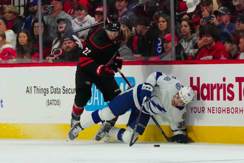 Nov 24, 2023; Raleigh, North Carolina, USA; Carolina Hurricanes defenseman Brett Pesce (22) checks Tampa Bay Lightning left wing Brandon Hagel (38) during the first period at PNC Arena. Mandatory Credit: James Guillory-USA TODAY Sports