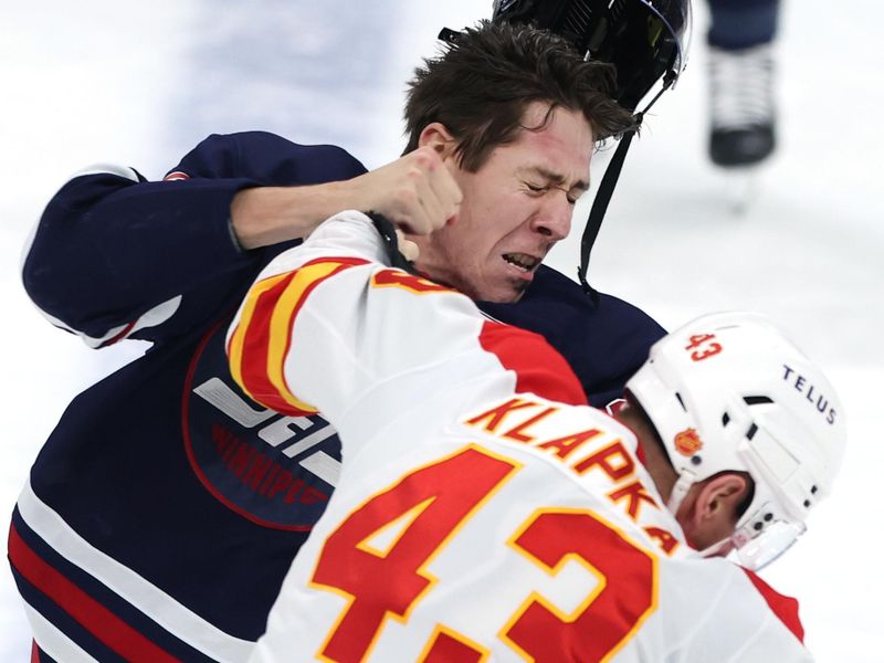 Oct 24, 2025; Winnipeg, Manitoba, CAN; Winnipeg Jets defenseman Logan Stanley (64) and Calgary Flames right wing Adam Klapka (43) fight in the first period at Canada Life Centre. Mandatory Credit: James Carey Lauder-Imagn Images