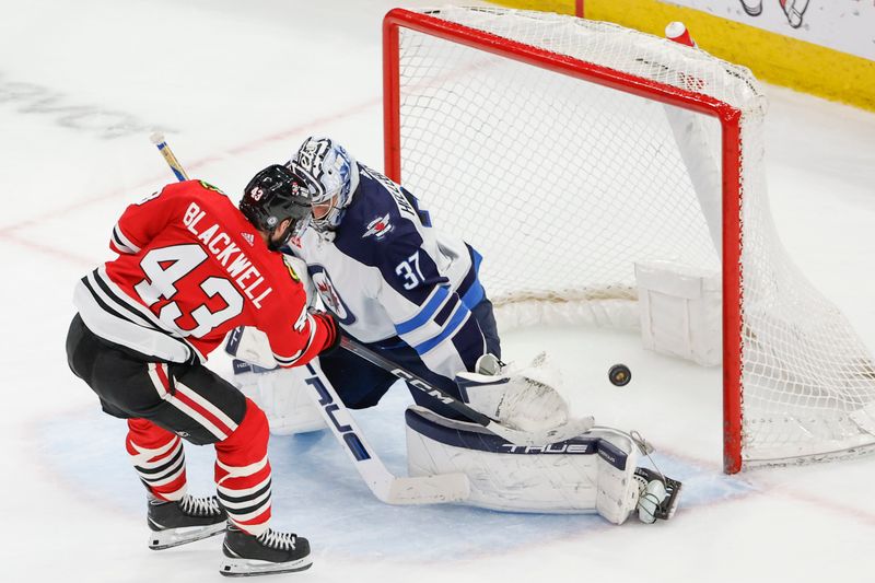 Feb 23, 2024; Chicago, Illinois, USA; Chicago Blackhawks center Colin Blackwell (43) shoots and scores against Winnipeg Jets goaltender Connor Hellebuyck (37) during the second period at United Center. Mandatory Credit: Kamil Krzaczynski-USA TODAY Sports