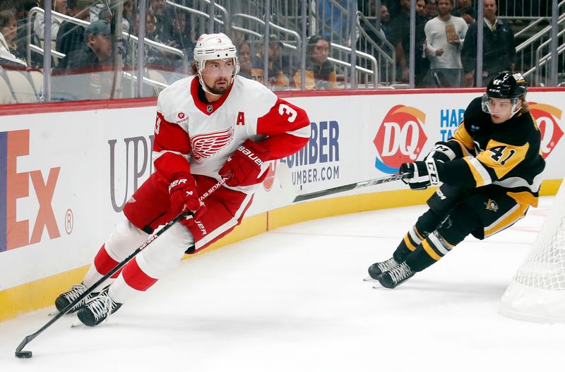 Oct 1, 2024; Pittsburgh, Pennsylvania, USA;  Detroit Red Wings defenseman Justin Holl (3)  skates with the puck as Pittsburgh Penguins right wing Ville Koivunen (41) chases during the first period at PPG Paints Arena. Mandatory Credit: Charles LeClaire-Imagn Images