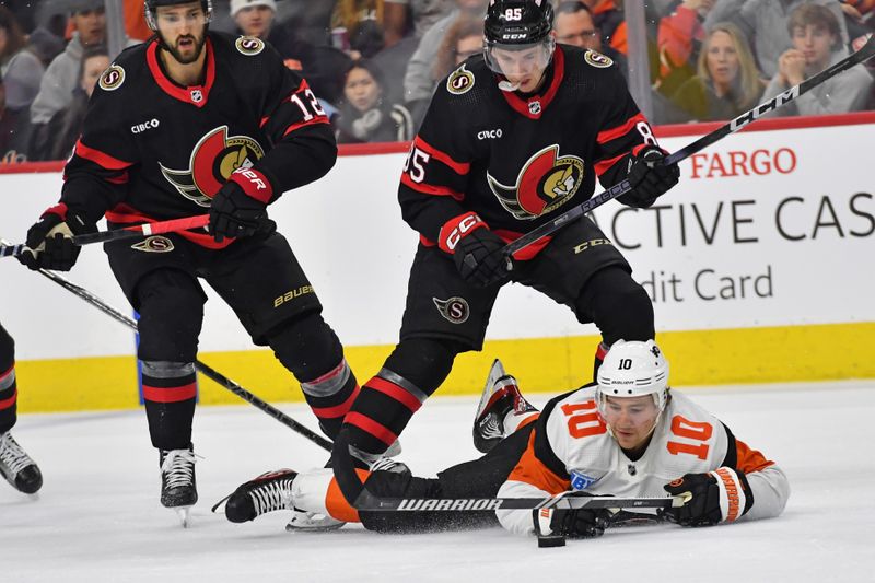 Mar 2, 2024; Philadelphia, Pennsylvania, USA; Philadelphia Flyers right wing Bobby Brink (10) tries to control the puck against Ottawa Senators defenseman Jake Sanderson (85) and center Mark Kastelic (12) during the first period at Wells Fargo Center. Mandatory Credit: Eric Hartline-USA TODAY Sports