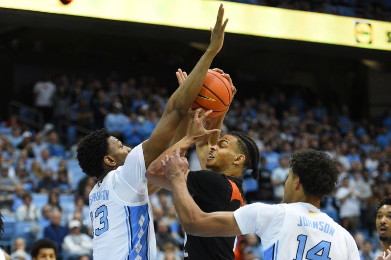 Feb 13, 2023; Chapel Hill, North Carolina, USA; Miami (Fl) Hurricanes guard Isaiah Wong (2) shoots as North Carolina Tar Heels forward Jalen Washington (13) and forward Puff Johnson (14) defend in the first half at Dean E. Smith Center. Mandatory Credit: Bob Donnan-USA TODAY Sports