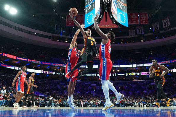 PHILADELPHIA, PENNSYLVANIA - DECEMBER 8: Dejounte Murray #5 of the Atlanta Hawks shoots the ball against Nicolas Batum #40 and Joel Embiid #21 of the Philadelphia 76ers in the first quarter at the Wells Fargo Center on December 8, 2023 in Philadelphia, Pennsylvania. The 76ers defeated the Hawks 125-114. NOTE TO USER: User expressly acknowledges and agrees that, by downloading and or using this photograph, User is consenting to the terms and conditions of the Getty Images License Agreement. (Photo by Mitchell Leff/Getty Images)