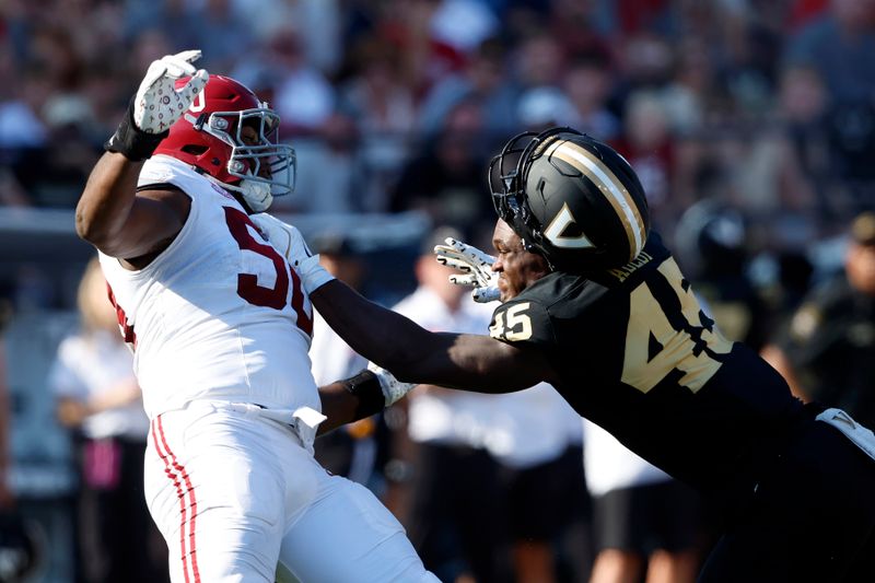 Oct 5, 2024; Nashville, Tennessee, USA;  Vanderbilt Commodores tight end Emmanuel Adebi (45) looses his helmet as he blocks Alabama Crimson Tide defensive lineman Tim Smith (50) during the first half at FirstBank Stadium. Mandatory Credit: Butch Dill-Imagn Images