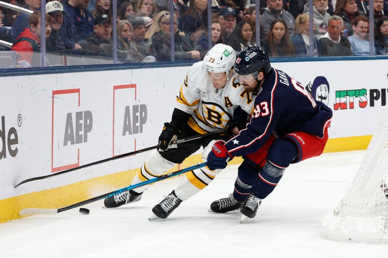 Mar 29, 2026; Columbus, Ohio, USA; Columbus Blue Jackets right wing Conor Garland (83) and Boston Bruins defenseman Charlie McAvoy (73) battle for the puck during the second period at Nationwide Arena. Mandatory Credit: Russell LaBounty-Imagn Images