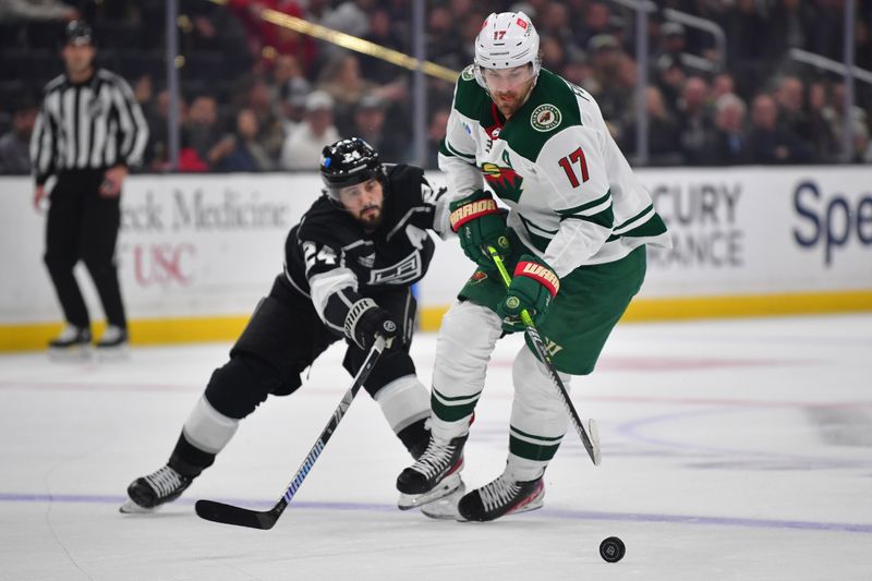 Mar 20, 2024; Los Angeles, California, USA; Minnesota Wild left wing Marcus Foligno (17) moves the puck ahead of Los Angeles Kings center Phillip Danault (24) during the first period at Crypto.com Arena. Mandatory Credit: Gary A. Vasquez-USA TODAY Sports