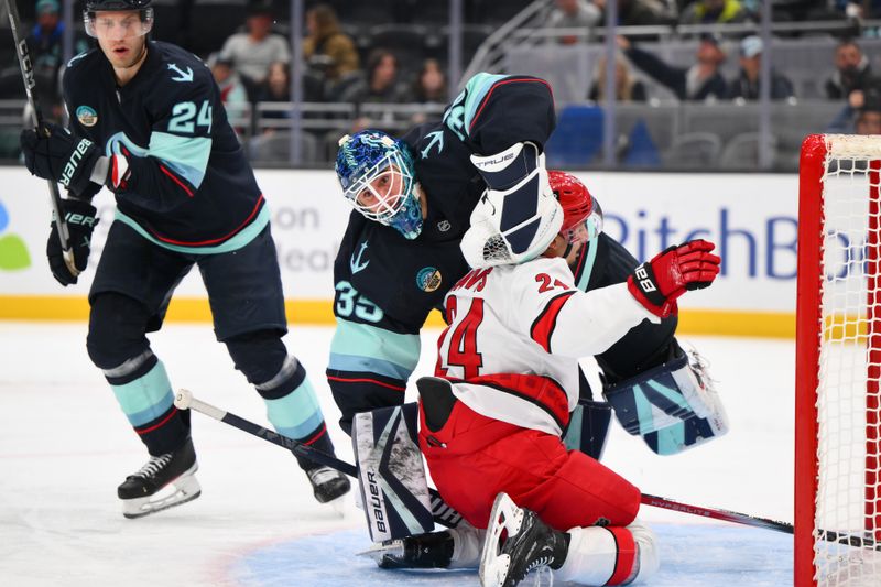 Oct 26, 2024; Seattle, Washington, USA; Carolina Hurricanes center Seth Jarvis (24) slides into Seattle Kraken goaltender Joey Daccord (35) during the second period at Climate Pledge Arena. Mandatory Credit: Steven Bisig-Imagn Images