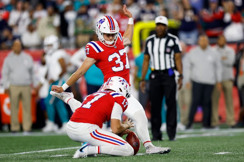 New England Patriots punter Bryce Baringer (17) holds the ball for place kicker Chad Ryland (37) during an extra point attempt in the second half of an NFL football game against the Miami Dolphins on Sunday, Sept. 17, 2023, in Foxborough, Mass. (AP Photo/Greg M. Cooper)