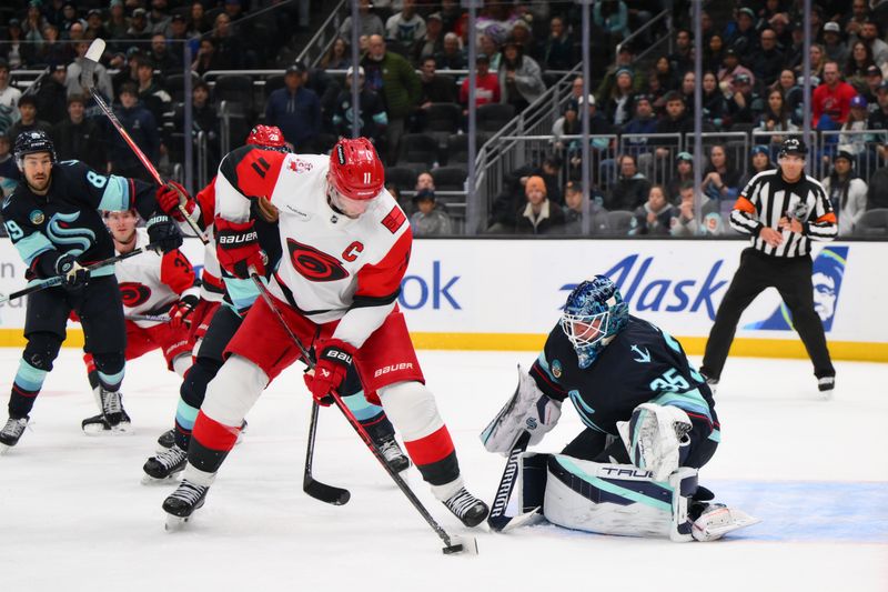 Mar 2, 2026; Seattle, Washington, USA; Carolina Hurricanes center Jordan Staal (11) plays the puck while defended by Seattle Kraken goaltender Joey Daccord (35) during the third period at Climate Pledge Arena. Mandatory Credit: Steven Bisig-Imagn Images