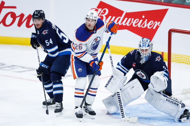 Sep 25, 2024; Winnipeg, Manitoba, CAN; Winnipeg Jets defenseman Dylan Samberg (54), Winnipeg Jets goalie Kaapo Kahkonen (34) and Edmonton Oilers forward Lane Pederson (26) look for the puck during the third period at Canada Life Centre. Mandatory Credit: Terrence Lee-Imagn Images