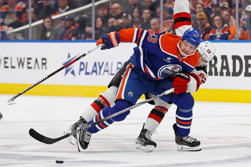 Nov 4, 2024; Edmonton, Alberta, CAN; New Jersey Devils defensemen Brett Pesce (22) tries to knock the puck away from Edmonton Oilers forward Mattias Janmark (13) during the first period at Rogers Place. Mandatory Credit: Perry Nelson-Imagn Images