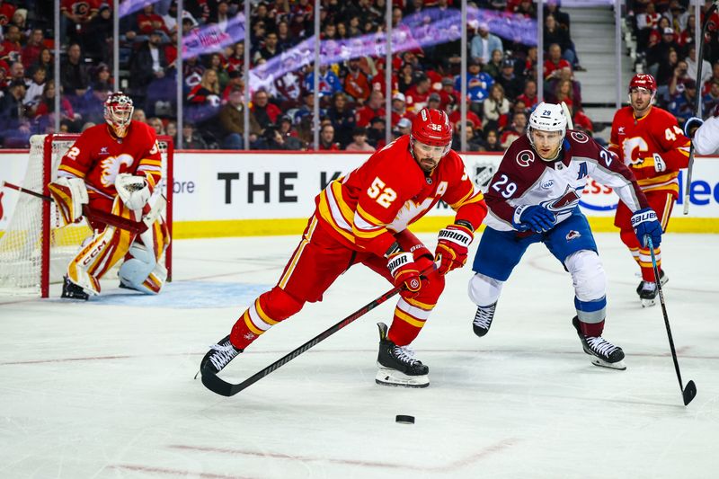Mar 14, 2025; Calgary, Alberta, CAN; Calgary Flames defenseman MacKenzie Weegar (52) and Colorado Avalanche center Nathan MacKinnon (29) battles for the puck during the third period at Scotiabank Saddledome. Mandatory Credit: Sergei Belski-Imagn Images