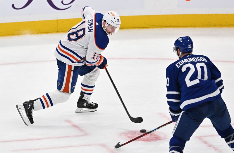 Mar 23, 2024; Toronto, Ontario, CAN; Edmonton Oilers forward Zach Hyman (18) skates with the puck against Toronto Maple Leafs defenseman Joel Edmundson (20) in the third period at Scotiabank Arena. Mandatory Credit: Dan Hamilton-USA TODAY Sports