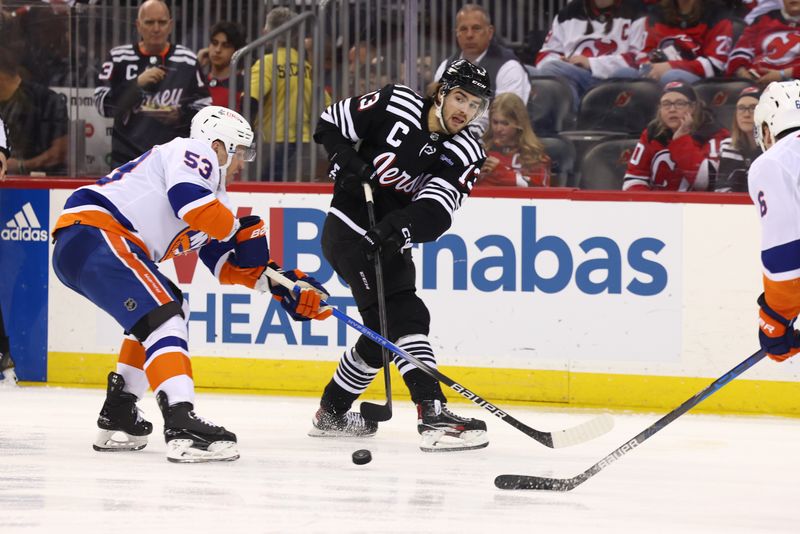 Apr 15, 2024; Newark, New Jersey, USA; New Jersey Devils center Nico Hischier (13) passes the puck while being defended by New York Islanders center Casey Cizikas (53) during the second period at Prudential Center. Mandatory Credit: Ed Mulholland-USA TODAY Sports