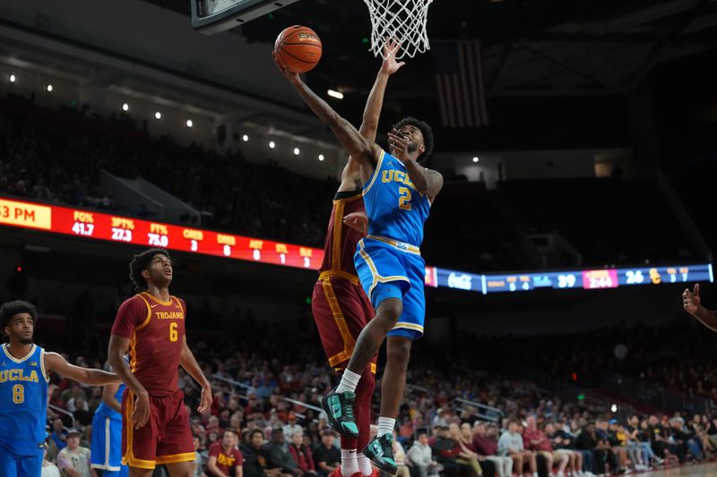 Mar 7, 2026; Los Angeles, California, USA; UCLA Bruins guard Donovan Dent (2) shoots the ball against Southern California Trojans forward Jacob Cofie (6) in the first half  at Galen Center. Mandatory Credit: Kirby Lee-Imagn Images