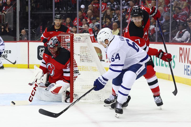 Oct 10, 2024; Newark, New Jersey, USA; New Jersey Devils goaltender Jacob Markstrom (25) knocks the puck away from Toronto Maple Leafs center David Kampf (64) during the first period at Prudential Center. Mandatory Credit: Ed Mulholland-Imagn Images