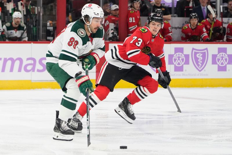 Jan 26, 2025; Chicago, Illinois, USA; Chicago Blackhawks left wing Lukas Reichel (73) defends Minnesota Wild center Frederick Gaudreau (89) during the first period at United Center. Mandatory Credit: David Banks-Imagn Images