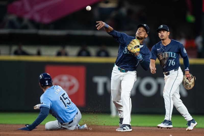 Aug 26, 2024; Seattle, Washington, USA; Seattle Mariners second baseman Jorge Polanco (7) attempts to turn a double play after forcing out right fielder Josh Lowe (15) at second base as Seattle Mariners shortstop Leo Rivas (76) watches during the fifth inning at T-Mobile Park. Mandatory Credit: Stephen Brashear-USA TODAY Sports