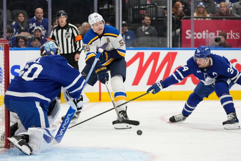 Oct 24, 2024; Toronto, Ontario, CAN; St. Louis Blues defenseman Colton Parayko (55) passes the puck as Toronto Maple Leafs forward Auston Matthews (34) and goaltender Joseph Woll (60) defendduring the second period at Scotiabank Arena. Mandatory Credit: John E. Sokolowski-Imagn Images