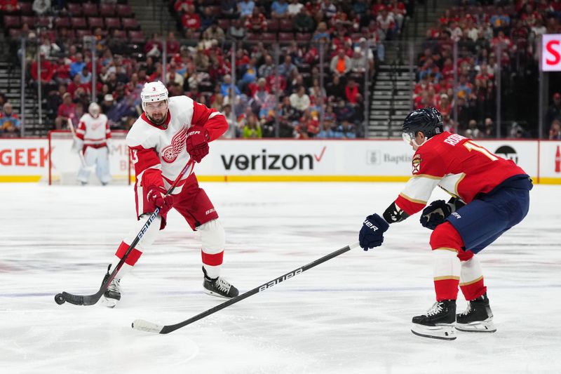 Jan 17, 2024; Sunrise, Florida, USA; Detroit Red Wings defenseman Justin Holl (3) passes the puck away from Florida Panthers center Evan Rodrigues (17) during the first period at Amerant Bank Arena. Mandatory Credit: Jasen Vinlove-USA TODAY Sports