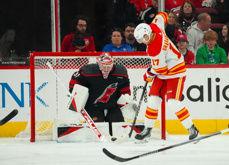 Mar 10, 2024; Raleigh, North Carolina, USA;  Carolina Hurricanes goaltender Frederik Andersen (31) makes a save on the deflection by Calgary Flames center Yegor Sharangovich (17) during the third period at PNC Arena. Mandatory Credit: James Guillory-USA TODAY Sports