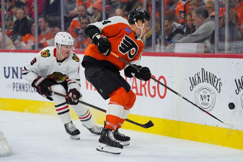 Nov 23, 2024; Philadelphia, Pennsylvania, USA; Philadelphia Flyers defenseman Nick Seeler (24) reaches for a loose puck against Chicago Blackhawks center Ryan Donato (8) in the second period at Wells Fargo Center. Mandatory Credit: Kyle Ross-Imagn Images