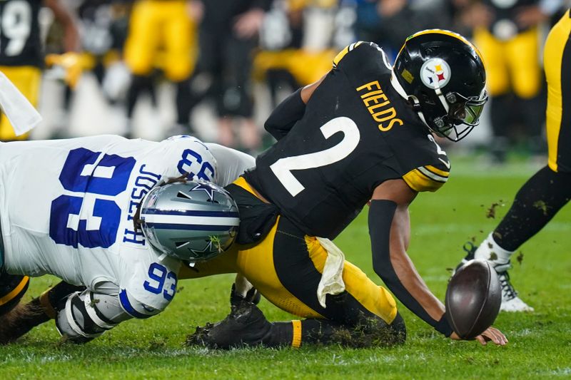 Pittsburgh Steelers quarterback Justin Fields (2) fumbles the ball while being hit by Dallas Cowboys defensive tackle Linval Joseph (93) during the first half of an NFL football game, Sunday, Oct. 6, 2024, in Pittsburgh. Fields recovered the fumble. (AP Photo/Matt Freed)