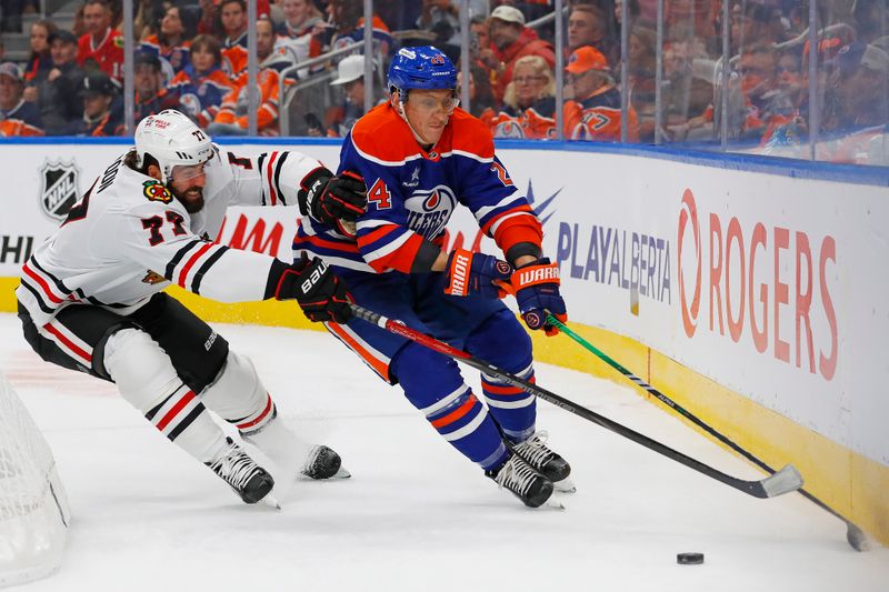 Oct 12, 2024; Edmonton, Alberta, CAN; Edmonton Oilers defensemen Travis Dermott (24) and Chicago Blackhawks forward Patrick Maroon (77) battle along the boards for a loose puck  during the second period at Rogers Place. Mandatory Credit: Perry Nelson-Imagn Images