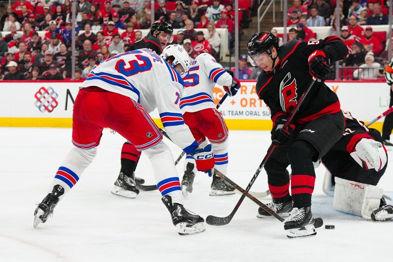 Apr 12, 2025; Raleigh, North Carolina, USA;  New York Rangers center Matt Rempe (73) and Carolina Hurricanes defenseman Scott Morrow (56) battle over the puck during the second period at Lenovo Center. Mandatory Credit: James Guillory-Imagn Images