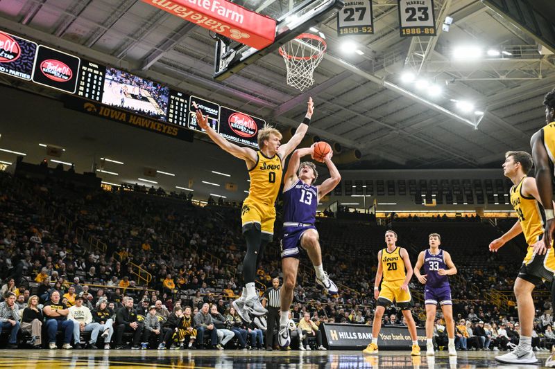 Dec 3, 2024; Iowa City, Iowa, USA; Northwestern Wildcats guard Brooks Barnhizer (13) goes to the basket as Iowa Hawkeyes forward Even Brauns (0) defends during the first half at Carver-Hawkeye Arena. Mandatory Credit: Jeffrey Becker-Imagn Images