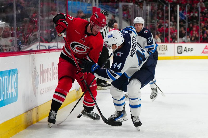 Mar 2, 2024; Raleigh, North Carolina, USA; Carolina Hurricanes right wing Andrei Svechnikov (37) and Winnipeg Jets defenseman Josh Morrissey (44) battle over the puck during the first period at PNC Arena. Mandatory Credit: James Guillory-USA TODAY Sports