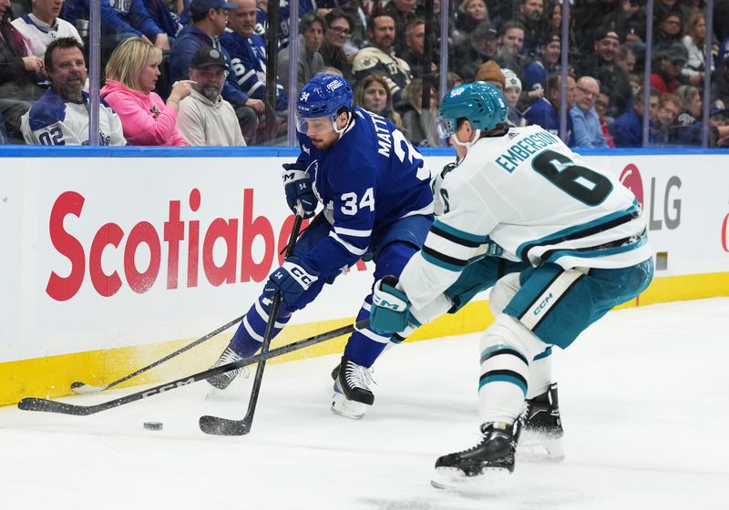 Jan 9, 2024; Toronto, Ontario, CAN; Toronto Maple Leafs center Auston Matthews (34) battles for the puck with San Jose Sharks defenseman Ty Emberson (6) during the first period at Scotiabank Arena. Mandatory Credit: Nick Turchiaro-USA TODAY Sports