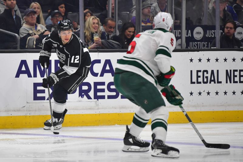 Mar 20, 2024; Los Angeles, California, USA; Los Angeles Kings left wing Trevor Moore (12) moves the puck against Minnesota Wild defenseman Jake Middleton (5) during the second period at Crypto.com Arena. Mandatory Credit: Gary A. Vasquez-USA TODAY Sports