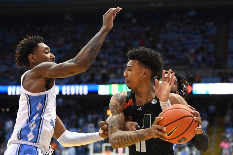 Feb 13, 2023; Chapel Hill, North Carolina, USA; Miami (Fl) Hurricanes guard Jordan Miller (11) with the ball as North Carolina Tar Heels forward Leaky Black (1) and guard R.J. Davis (4) pressure in the second half at Dean E. Smith Center. Mandatory Credit: Bob Donnan-USA TODAY Sports