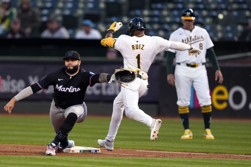 May 3, 2024; Oakland, California, USA; Oakland Athletics center fielder Esteury Ruiz (1) reaches on an infield RBI single as the throw gets past Miami Marlins first baseman Emmanuel Rivera (left) during the fifth inning at Oakland-Alameda County Coliseum. Mandatory Credit: Darren Yamashita-USA TODAY Sports