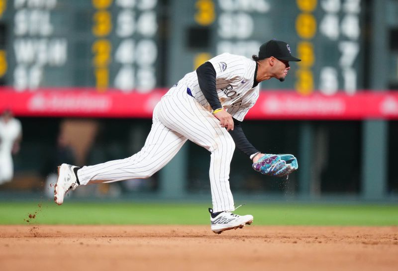 Apr 9, 2024; Denver, Colorado, USA; Colorado Rockies shortstop Ezequiel Tovar (14) fields the ball in the sixth inning against the Arizona Diamondbacks  at Coors Field. Mandatory Credit: Ron Chenoy-USA TODAY Sports