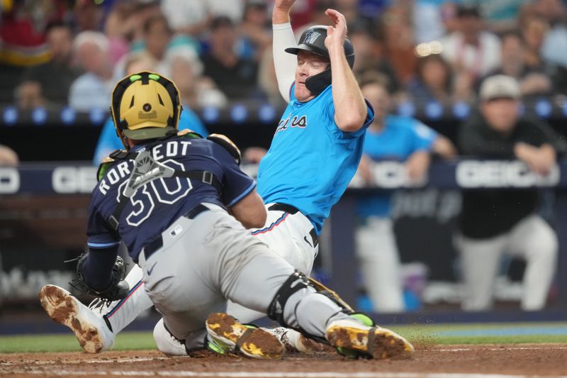 May 18, 2025; Miami, Florida, USA;  Miami Marlins left fielder Eric Wagaman (33) gets tagged out at the plate by Tampa Bay Rays catcher Ben Rortvedt (30) in the second inning at loanDepot Park. Mandatory Credit: Jim Rassol-Imagn Images