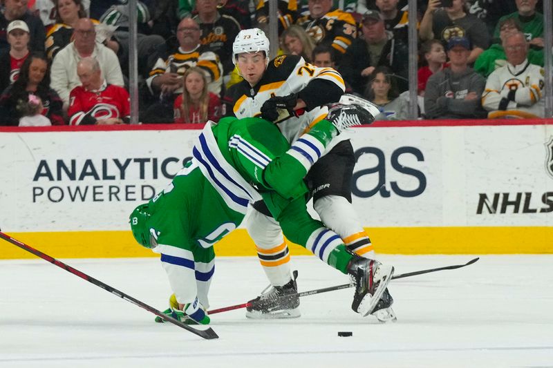 Mar 26, 2023; Raleigh, North Carolina, USA;  Boston Bruins defenseman Charlie McAvoy (73) checks Carolina Hurricanes defenseman Brett Pesce (22) during the first period at PNC Arena. Mandatory Credit: James Guillory-USA TODAY Sports