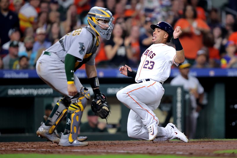 Sep 13, 2023; Houston, Texas, USA; Houston Astros designated hitter Michael Brantley (23) slides across home plate to score a run against the Oakland Athletics during the fifth inning at Minute Maid Park. Mandatory Credit: Erik Williams-USA TODAY Sports