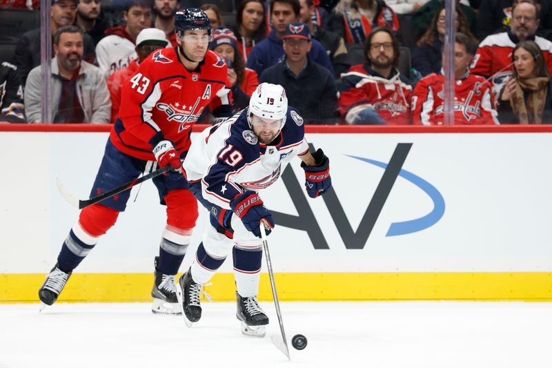 Nov 24, 2025; Washington, District of Columbia, USA; Columbus Blue Jackets center Adam Fantilli (19) reaches for the puck in front of Washington Capitals right wing Tom Wilson (43) during the first period at Capital One Arena. Mandatory Credit: Geoff Burke-Imagn Images