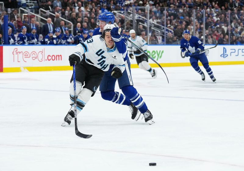 Nov 5, 2025; Toronto, Ontario, CAN; Toronto Maple Leafs defenseman Brandon Carlo (25) battles for the puck with Utah Mammoth left wing Brandon Tanev (13) during the second period at Scotiabank Arena. Mandatory Credit: Nick Turchiaro-Imagn Images