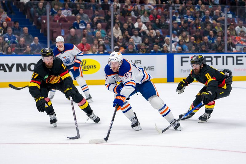 Nov 9, 2024; Vancouver, British Columbia, CAN; Edmonton Oilers forward Connor McDavid (97) drives between Vancouver Canucks defenseman Filip Hronek (17) and forward Conor Garland (8) during the first period at Rogers Arena. Mandatory Credit: Bob Frid-Imagn Images