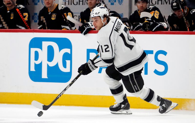 Feb 18, 2024; Pittsburgh, Pennsylvania, USA;  Los Angeles Kings left wing Trevor Moore (12) skates with the puck against the Pittsburgh Penguins during the first period at PPG Paints Arena. Mandatory Credit: Charles LeClaire-USA TODAY Sports